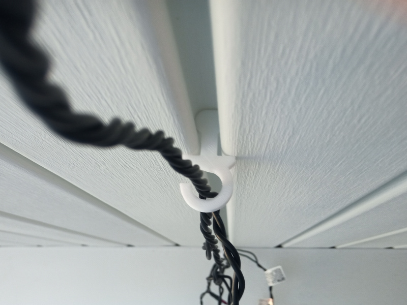Hook clipped into bead of porch ceiling, with a string of Christmas lights hanging from it